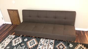 Un canapé marron, avec un tapis à motifs devant.
