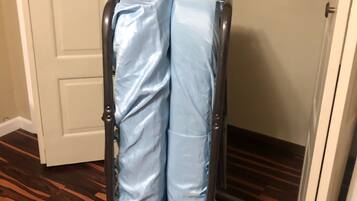 A metal cart with a blue cover, positioned in a hallway with wooden flooring and a white door in the background.