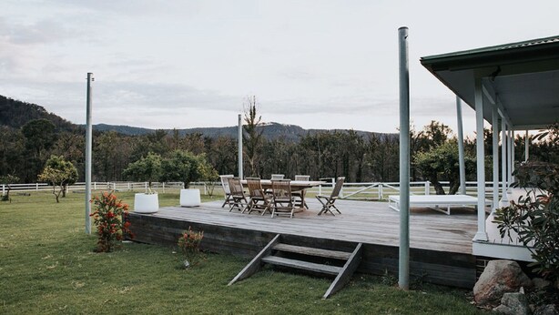 A wooden deck with outdoor furniture, a covered seating area, and a view of a mountainous landscape.