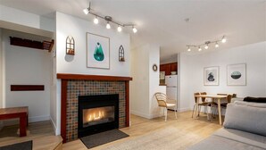 A living room with a fireplace, a dining area with a table and chairs, and a sofa.
