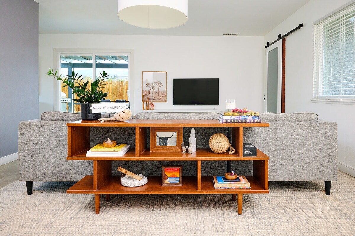 A living room with a grey sofa, wooden coffee table, and a TV on the wall.
