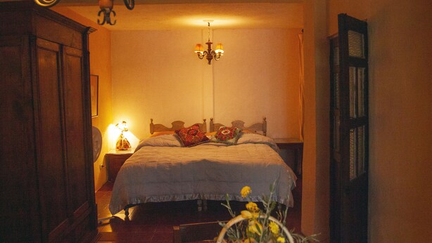 Un dormitorio con cama, mesita de noche, lámpara y candelabro.