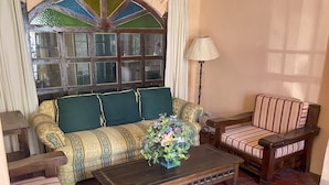 Una sala de estar acogedora con un sofá estampado, un sillón a rayas, una mesa de centro de madera y una planta en maceta.