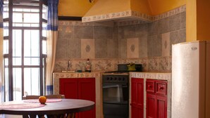 Una cocina con armarios rojos, estufa y refrigerador.