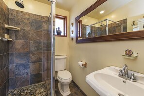 Ein Badezimmer mit Dusche, Toilette, Waschbecken und Spiegel.
