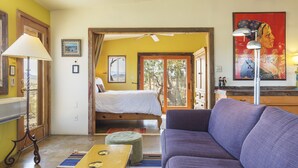 A room with a bed, a sofa, a lamp, and a painting on the wall.