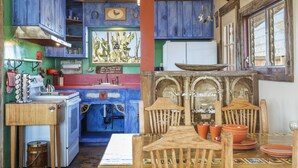 A rustic kitchen with wooden cabinets, a stove, and a dining table set with orange plates and bowls.
