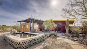 A desert-style building with a pool, surrounded by cacti and rocks.