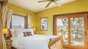 A bedroom with a wooden bed, a ceiling fan, and a large sliding glass door to the outside.
