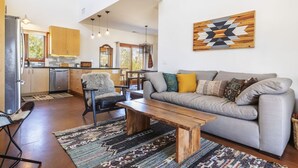 A modern living room with a grey sofa, wooden coffee table, and patterned rug. - MoonView Modern | Hot tub, BBQ & Private Pool! (Joshua Tree)