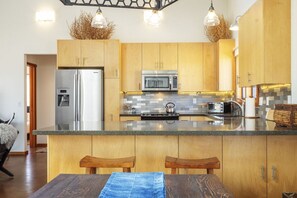 Een moderne keuken met houten kastjes, roestvrijstalen apparatuur en een centraal eiland met zitplaatsen.