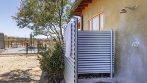 A covered outdoor area with a pool, a metal gate, and a showerhead. - MoonView Modern | Hot tub, BBQ & Private Pool! (Joshua Tree)