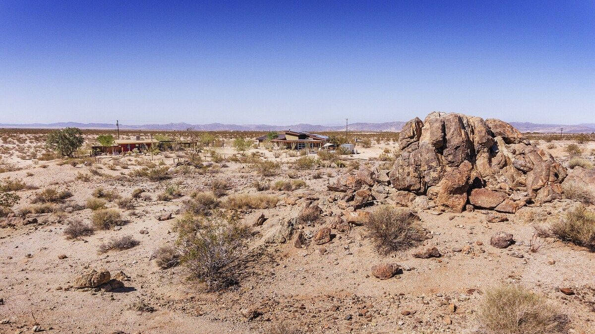 A desert landscape with a small building and a prominent rock formation.
