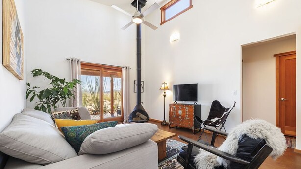 A living room with a sofa, a chair, a television, and a fireplace. - MoonView Modern | Hot tub, BBQ & Private Pool! (Joshua Tree)
