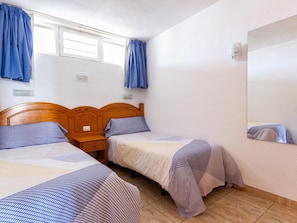 A bedroom with two single beds, wooden headboards, and a large mirror on the wall.
