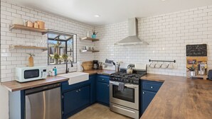 A kitchen with white subway tiles, blue cabinets, stainless steel appliances, and wooden countertops. - Cosmic Rabbit - Family Friendly home w/Hot Tub (Joshua Tree)
