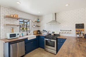 A kitchen with white subway tiles, blue cabinets, stainless steel appliances, and wooden countertops. - Cosmic Rabbit - Family Friendly home w/Hot Tub (Joshua Tree)