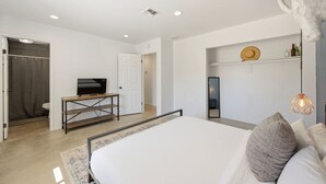 A bedroom with a bed, a television on a stand, a wardrobe, and a shelf with decorative items. - Cosmic Rabbit - Family Friendly home w/Hot Tub (Joshua Tree)