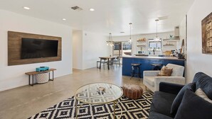 A modern living room with a large TV, a glass coffee table, a patterned rug, and a sofa. - Cosmic Rabbit - Family friendly home w/Hot Tub (Joshua Tree)
