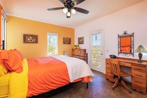 A bedroom with a bed, a desk, and a ceiling fan.