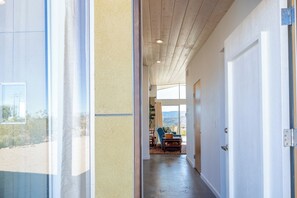 A hallway leading to a room with a view, a door with a handle, and a ceiling with recessed lighting.