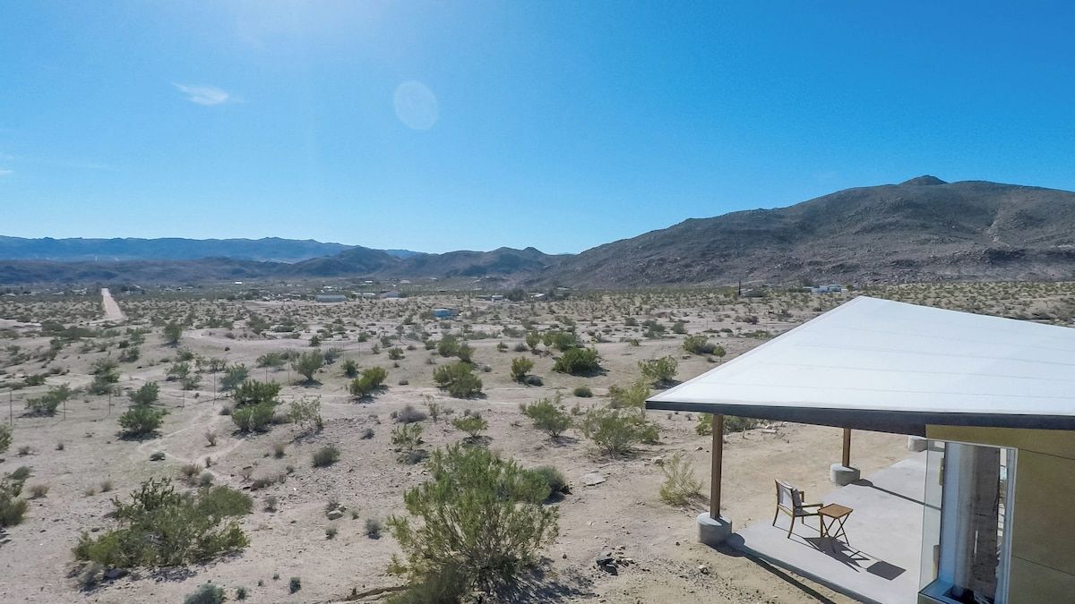Un paysage désertique avec une végétation clairsemée et des montagnes à l’horizon.