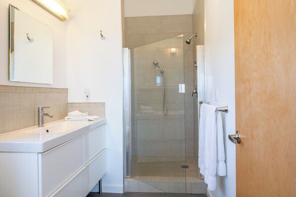 A modern bathroom with a glass-enclosed shower, a white sink, and a mirror.