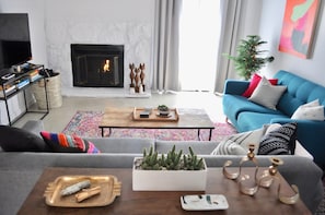 A living room with a fireplace, a blue sofa, a coffee table, and a television.