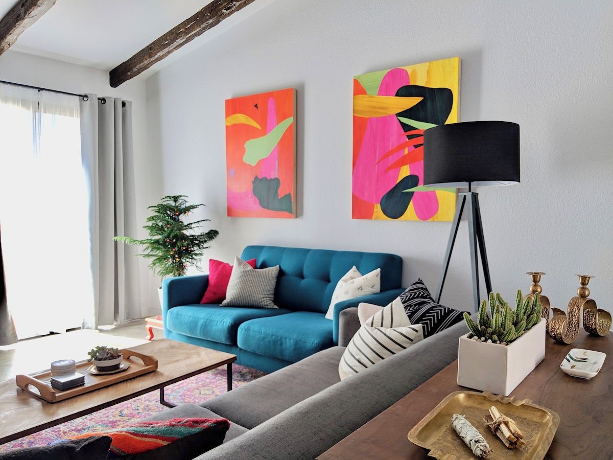 A modern living room with a blue sofa, a coffee table, a floor lamp, and two abstract paintings on the wall.