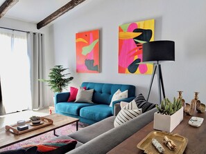 A modern living room with a blue sofa, a coffee table, a floor lamp, and two abstract paintings on the wall. - Campero House: Meditation Room & Near Joshua Tree (Yucca Valley)