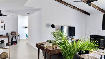 Een moderne woonkamer met een open haard, een televisie en een eethoek met een tafel en stoelen.