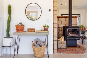 A living room with a fireplace, a cactus, and a mirror on the wall.