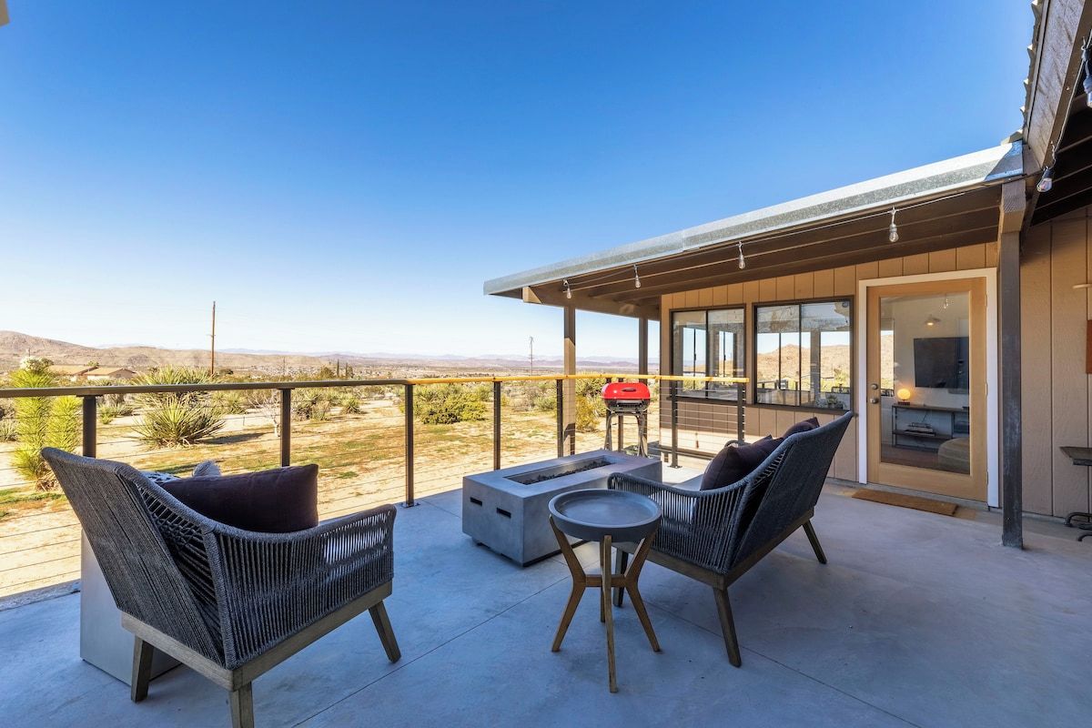 A balcony with wicker furniture, a fire pit, and a view of the desert.