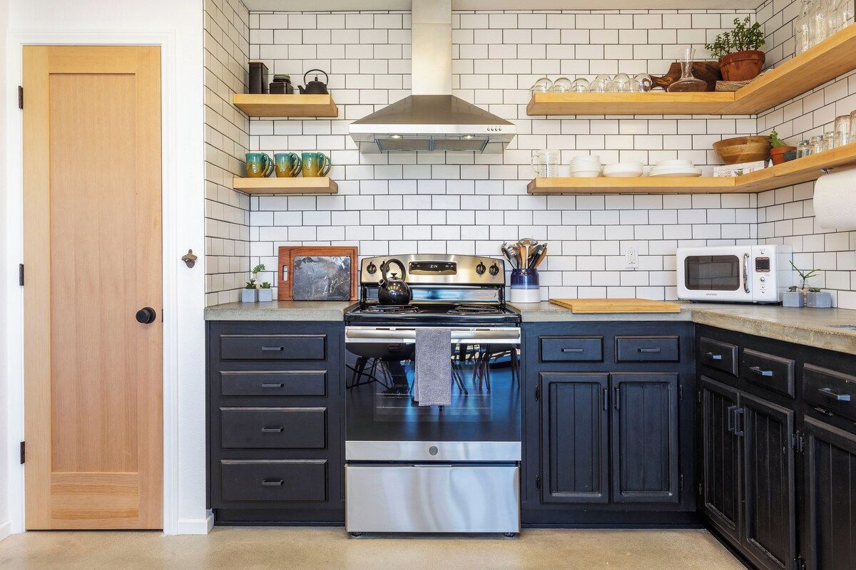 A kitchen with a stove, microwave, and wooden shelves above.