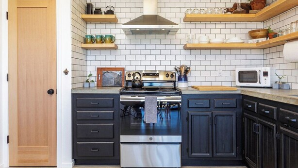 A kitchen with a stove, microwave, and wooden shelves above.