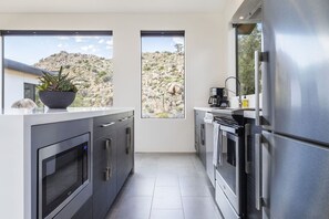 Eine moderne Küche mit Edelstahlgeräten, einem großen Fenster und einem Topf mit Pflanze.