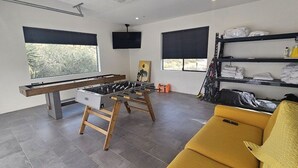 Un salon moderne avec une table de baby-foot, un canapé et un téléviseur.