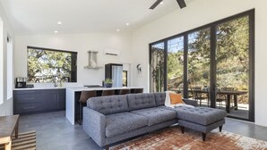 Un espace de vie moderne comprenant un canapé d’angle gris, un coin repas et une cuisine.