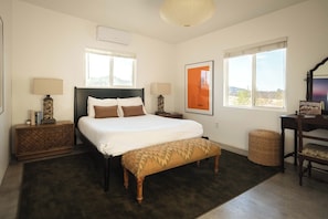 Ein Schlafzimmer mit einem großen Bett, zwei Nachttischen, einer Bank und einem Fenster mit Blick.