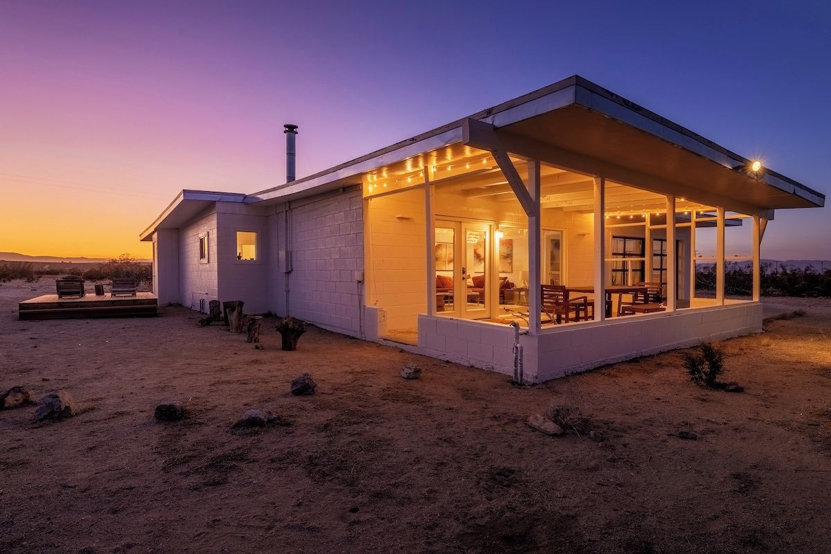 A modern house with a covered patio, a fireplace, and a view of the desert landscape.