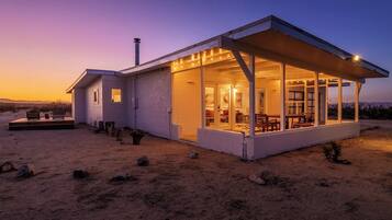 A modern house with a covered patio, a fireplace, and a view of the desert landscape.