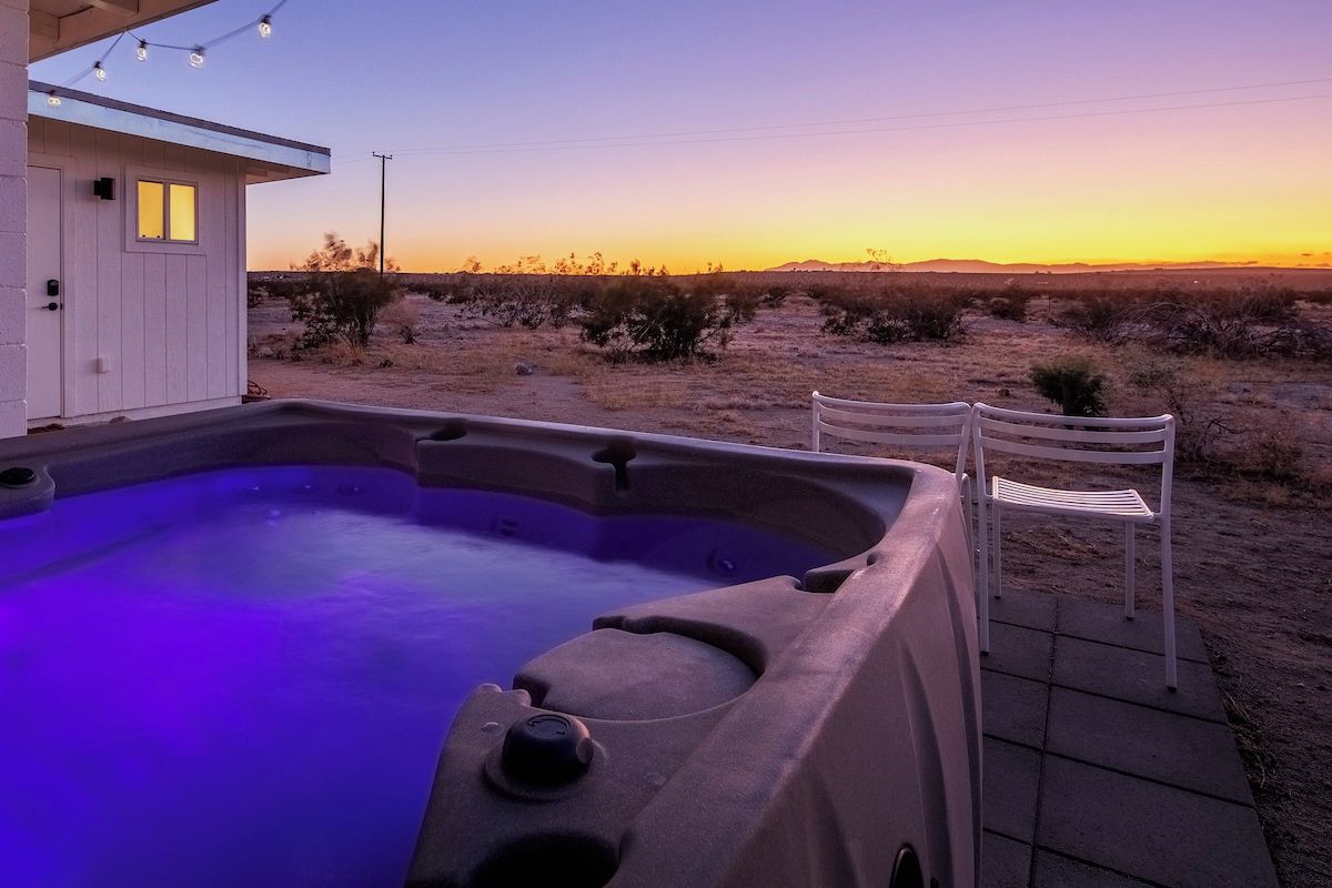 A hot tub with a view of a desert landscape at sunset.