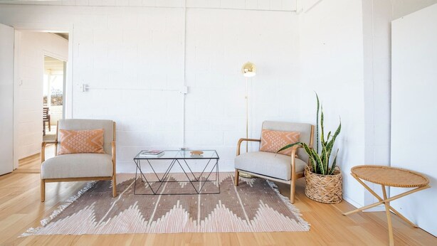 Un salon moderne comprenant deux fauteuils, une table basse, un lampadaire et une petite table ronde.