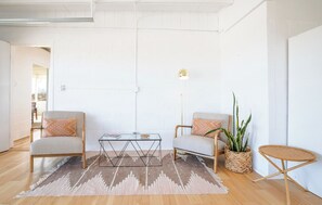 A modern living room with two armchairs, a coffee table, a floor lamp, and a small round table.