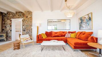 Ein Wohnzimmer mit einer Steinwand, einem roten Sofa, einem weißen Couchtisch und einer Chandelier.