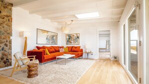 Un salon moderne avec un plancher en bois, un canapé rouge et un tapis blanc.