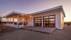 Une maison moderne dotée d’un patio couvert, de grandes fenêtres et d’un garage.