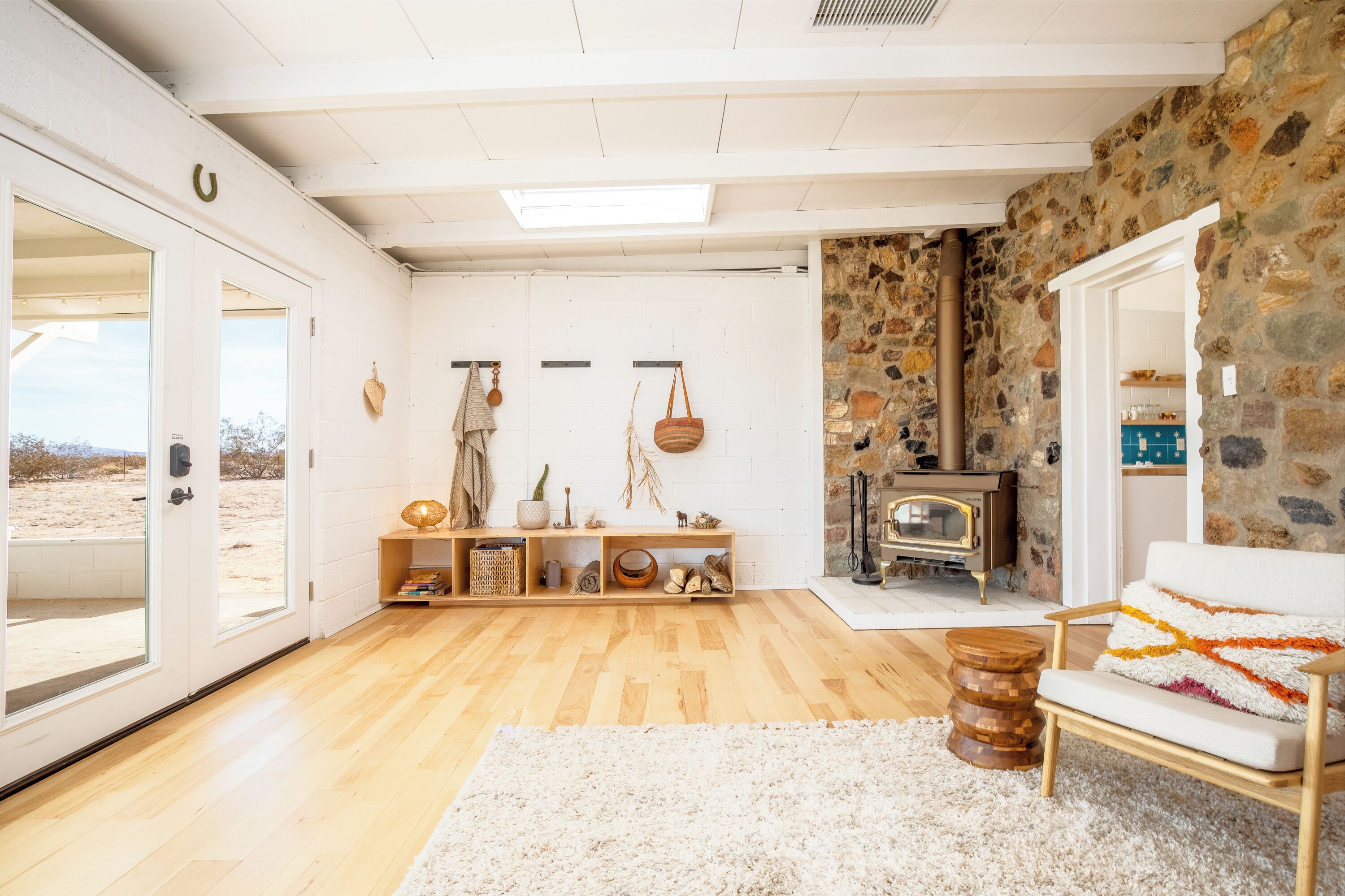 Ein geräumiger Raum mit Holzboden, einem weißen Sofa, einer Steinwand und einem Kamin.