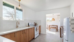 A modern kitchen with white cabinetry, a built-in oven, and a large window. - Mojave Mesa - Secluded Desert Home Near Joshua Tree (Yucca Valley)