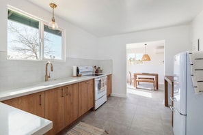 Een moderne keuken met witte kasten, een inbouwoven en een groot raam.